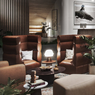 Two brown leather armchairs in a modern lounge.