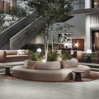 Lounge area with curved sofa, trees, and artwork.