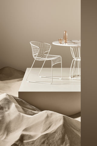 ND cropped chair and table set against a neutral wall with sandstone textures.