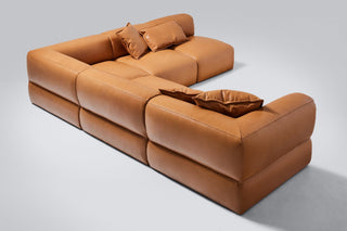 Brown leather sectional sofa with pillows.