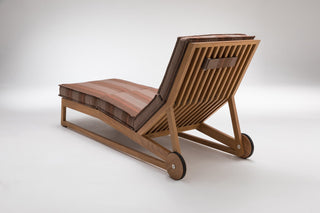 Wooden chaise lounge with striped cushion.