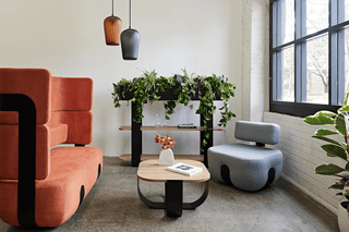 Modern office lounge with seating, plants, and window.