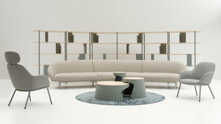Modern living room with a beige sofa, two gray chairs, and a round coffee table on a white background.