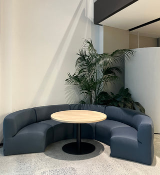 Modern office seating area with round table and plants.