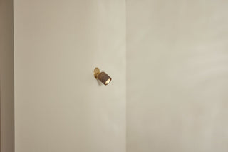 Marz Designs Terra-1 brass articulating wall light on a white wall.