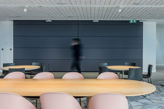 Modern office interior with person walking past tables.