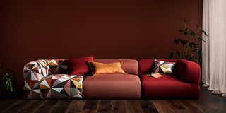 Puffalo sofa with geometric patterned armrest and red cushions.