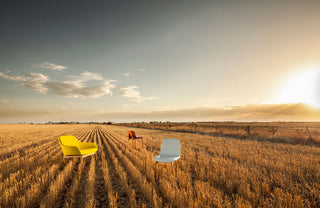 Three chairs in a field with a sunset sky