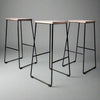 Three bar stools with black metal legs and wooden seats on a grey background