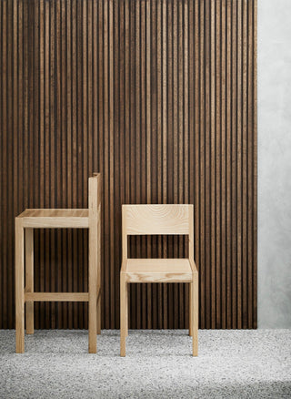 Two wooden chairs in front of a wood-paneled wall.