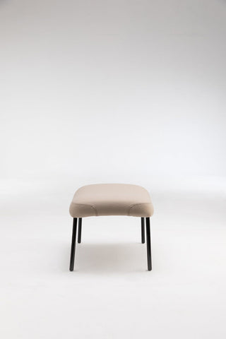 Beige upholstered stool with black legs.
