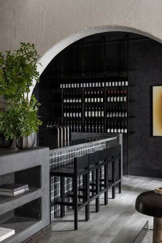 Wine bar with bottles, stools, and arched doorway.