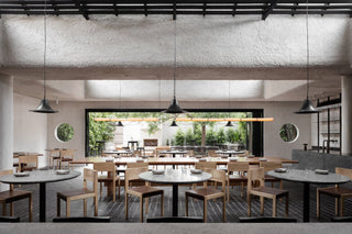 Restaurant dining room with tables, chairs, and hanging lights.