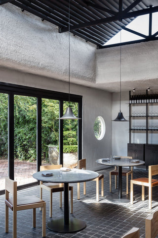 Restaurant interior with tables, chairs, and hanging lamps.