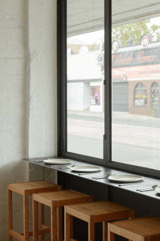 Wooden stools by a window with plates.