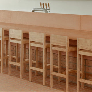 Wooden bar stools at a counter with a tap.