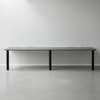 Long dark gray table with black legs on a light gray floor and white wall background
