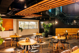 Interior of a modern bar with tables and plants.