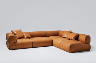 Brown leather sectional sofa with pillows.