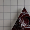 Red marble triangle with gray tile background.