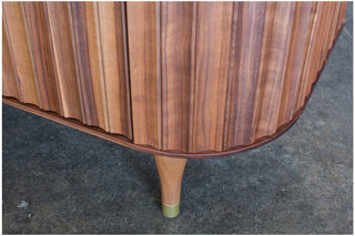Detail of mid-century modern wood cabinet with ridged doors and gold-tipped...