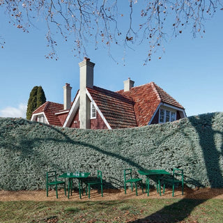 Fable outdoor seating with a red-roofed house behind a hedge