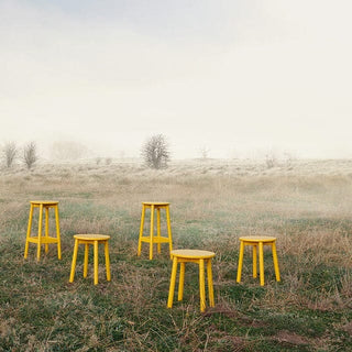 Five yellow stools in a field.