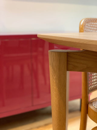 Wooden table leg and chair in front of a red cabinet.
