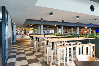 Modern restaurant interior with tables and stools.