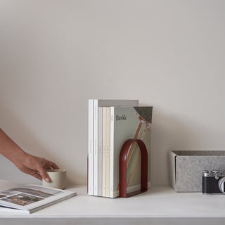 Books in a red bookend on a white shelf