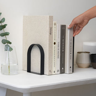 Books held by hand on a white table, Passage4