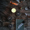 Traveltins Southern Nomad Co. candle tins with candle, feather, and book