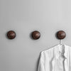 Three wooden wall hooks holding a shirt