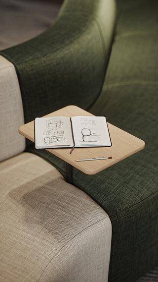 Notebook and pen on a small table attached to a green couch.